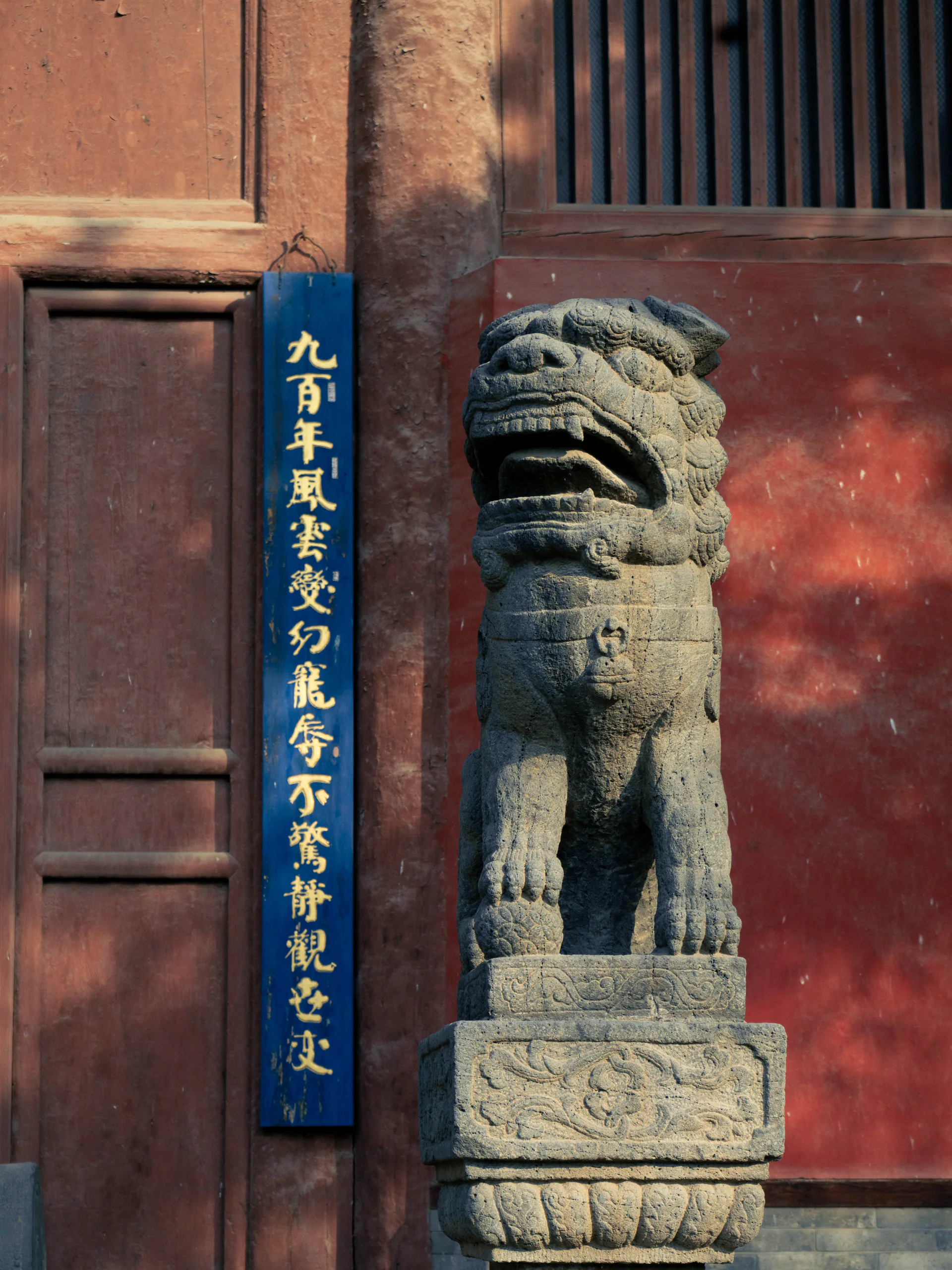 红色建筑门口的石雕守护兽与竖幅文字