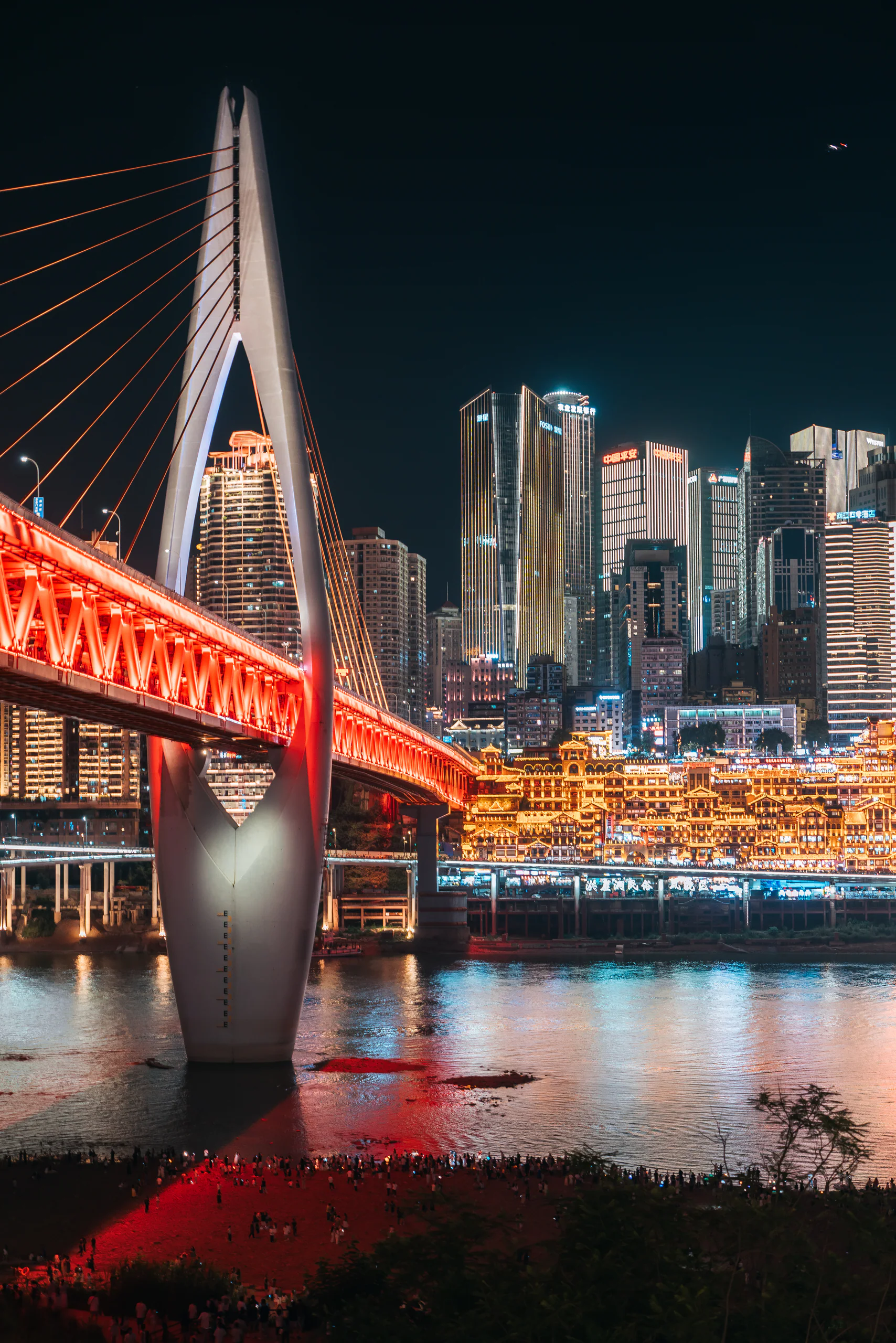 红色灯光照亮的桥梁与夜间城市天际线